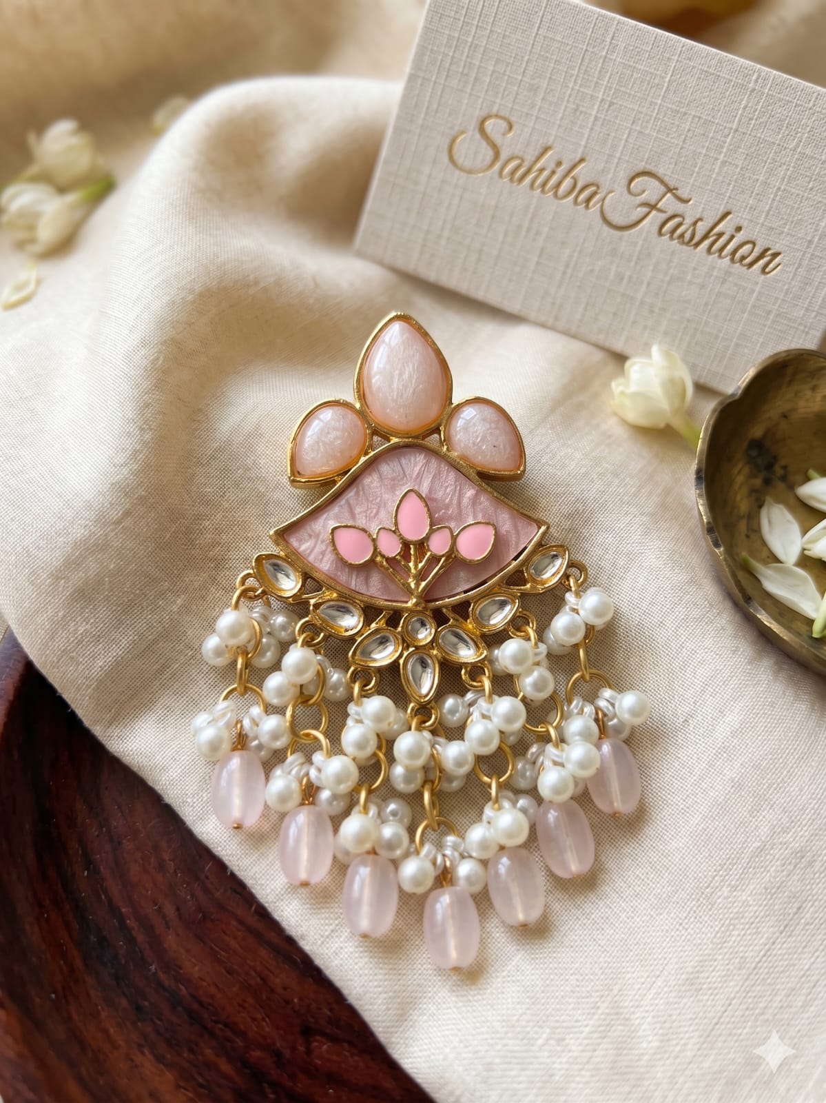 baby pink kundan pearl tassel earrings for women | ethnic fusion statement earrings Baby Pink Kundan Drop Earrings with pearl bead danglers and gold-tone detailing displayed on a soft beige fabric background.