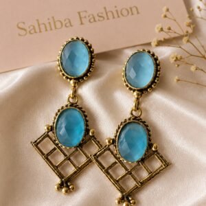 Pair of vintage-style antique gold drop earrings featuring oval sky blue stones and geometric grid patterns on a satin cloth background.