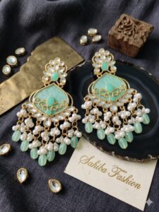 Heavy mint green kundan chandbali earrings with intricate gold filigree and pearl bead tassels.