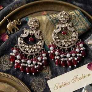 Peacock motif kundan earrings with deep maroon beads and white pearl accents.