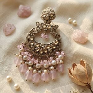 Gold-toned chandelier earrings featuring leaf-shaped crystals and hanging pink teardrop beads.
