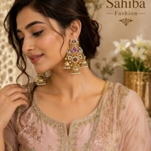 Indian woman wearing gold pink stone pearl jhumka chandbali statement earrings styled with a pastel pink embroidered suit.