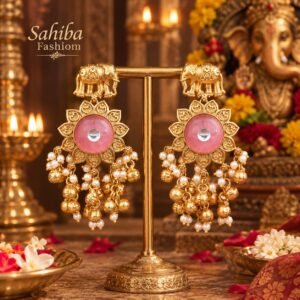 Sahiba Fashion gold elephant earrings with pink center stone and pearl ghungroo drops on a display stand in a temple setup.