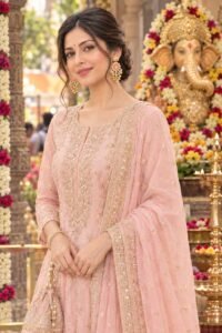 Model wearing gold elephant motif earrings with pink centerpiece paired with a pink embroidered suit.