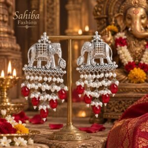Sahiba Fashion silver elephant motif earrings with white pearl and red bead drops on a metal display stand in a temple setting.