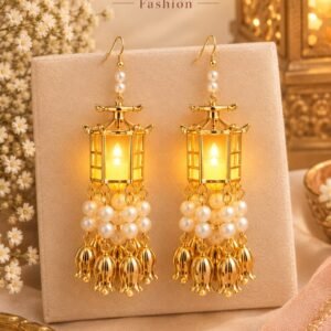 Sahiba Fashion gold LED light lantern jhumka earrings with pearls displayed on an angled beige suede board beside an ornate brass tray.
